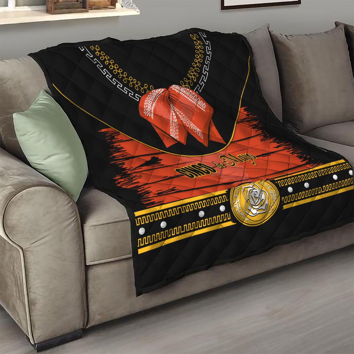 Charro quilt draped on sofa, black fabric with orange band, red bow, gold emblem