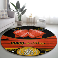 Black round carpet rug with 'Cinco de Mayo' lettering and orange bow in center