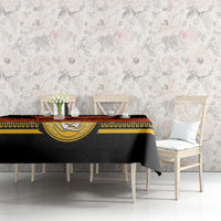 Black Cinco de Mayo tablecloth with gold medallion stripe and red banner near table corner