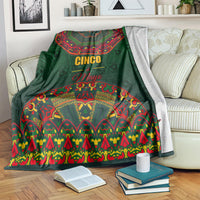 Green Mexican folk pattern blanket with Cinco de Mayo graphic, draped on sofa