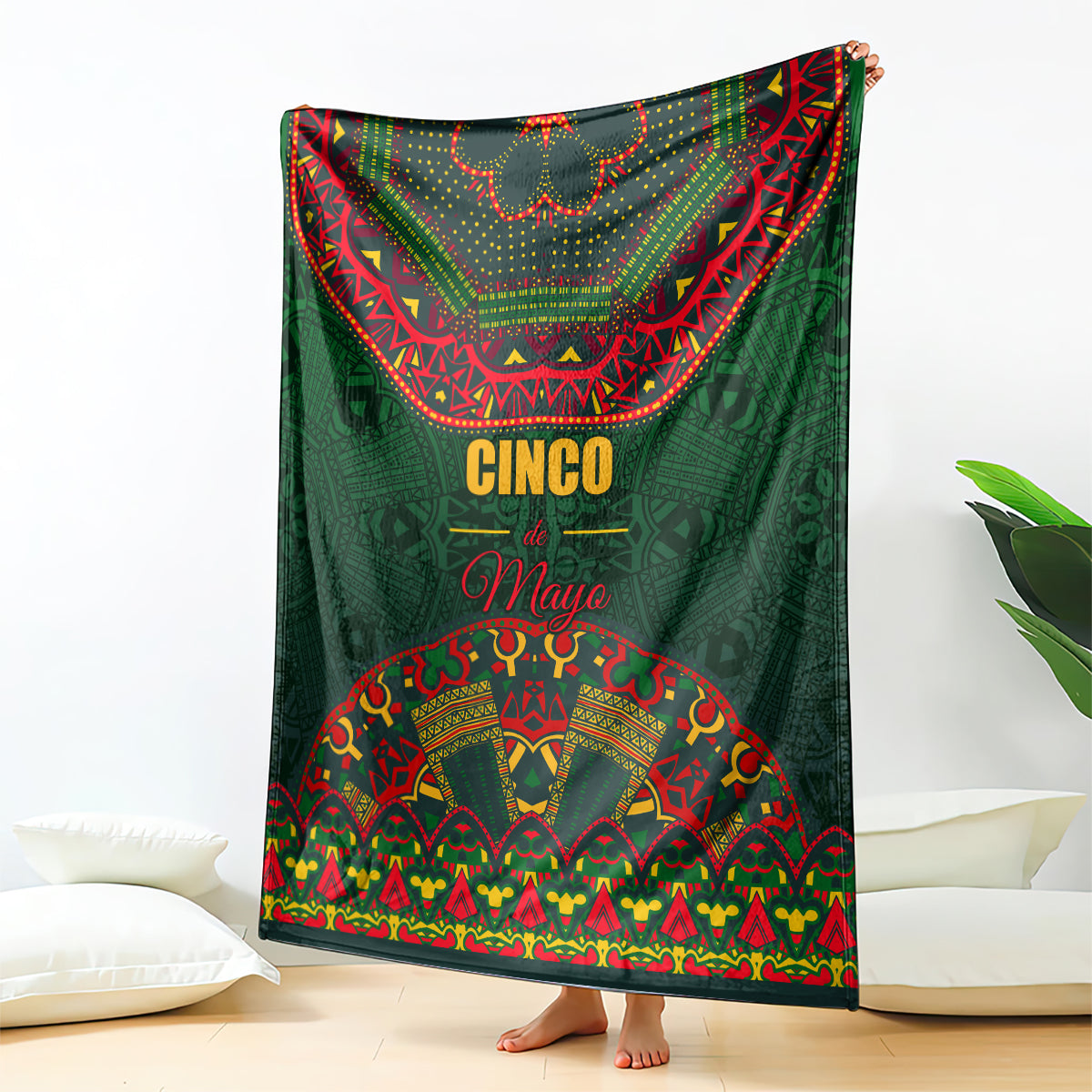 Green Cinco de Mayo blanket with colorful folk border, hanging over couch