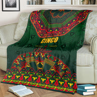 Green folk pattern blanket with 'Cinco de Mayo' text, laid over striped couch
