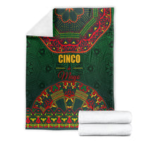 Green Cinco de Mayo blanket with colorful folk print, folded with white towels