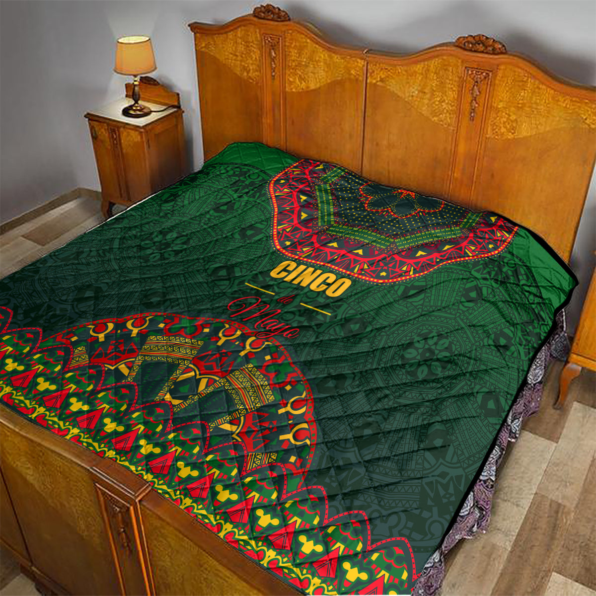 Green quilt on bed with red-and-yellow folk medallion and 'Cinco Mayo' text