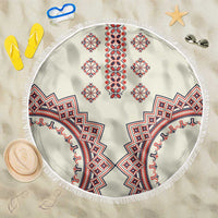 Round beige beach blanket with fringe edge and red, blue, white traditional geometric pattern