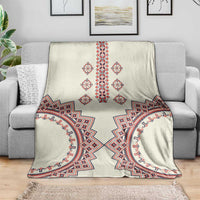 Beige traditional pattern blanket draped on a sofa with red, blue, white motifs