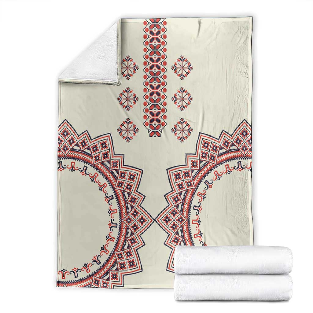 Beige blanket with red and blue geometric design, neatly folded beside white rolls
