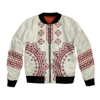 Beige bomber jacket with embroidered folk pattern front, black ribbed cuffs and hem