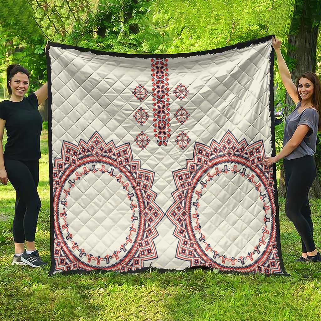 White quilt with quilted diamond texture and red, white, blue cross-and-oval traditional patterns