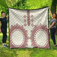 White quilt with quilted diamond texture and red, white, blue cross-and-oval traditional patterns