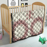 White quilt for baby bed with diamond quilting and red, navy, and blue oval medallion patterns