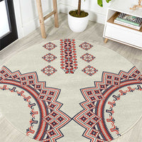 Beige round rug with Romanian-style geometric embroidery pattern in red, blue, and white