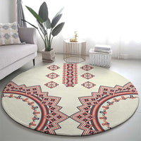 Beige round rug with symmetric geometric embroidery in red, blue, and white, wide view