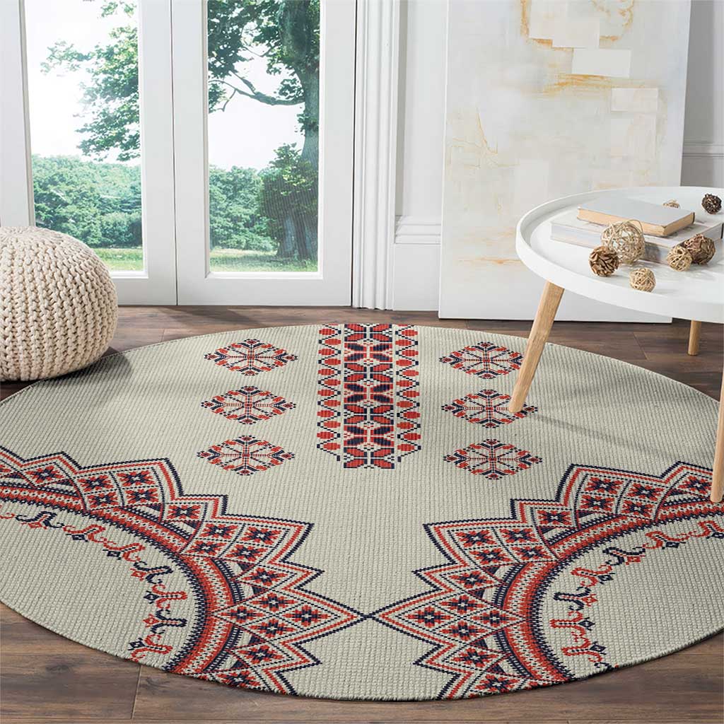 Beige round rug with large red, blue, and white geometric border and center motifs