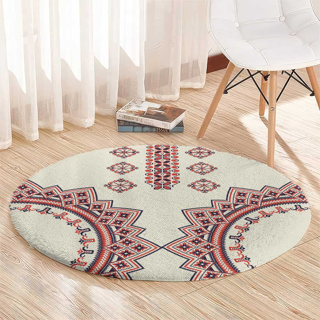 Beige round rug with red, blue, and white geometric center and corner medallions