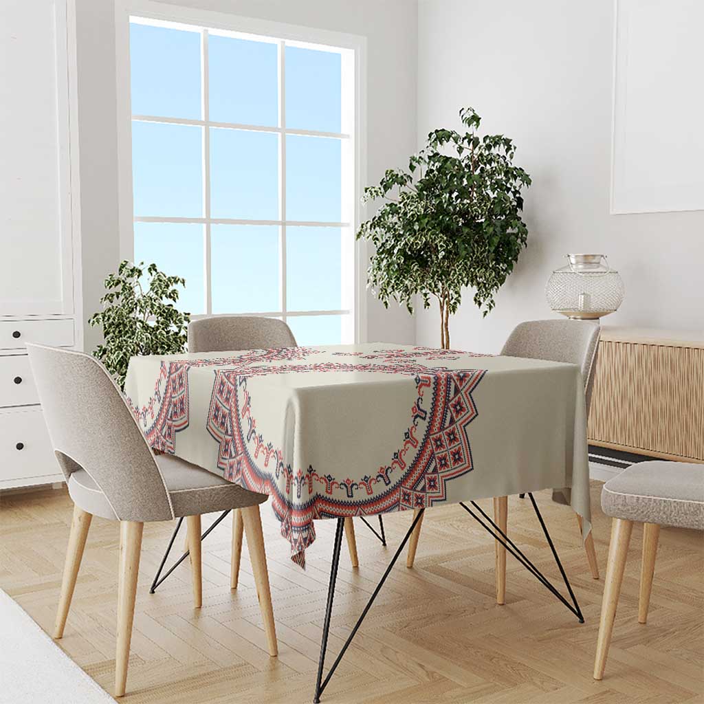 Beige tablecloth with red and blue geometric trim, laid on dining table