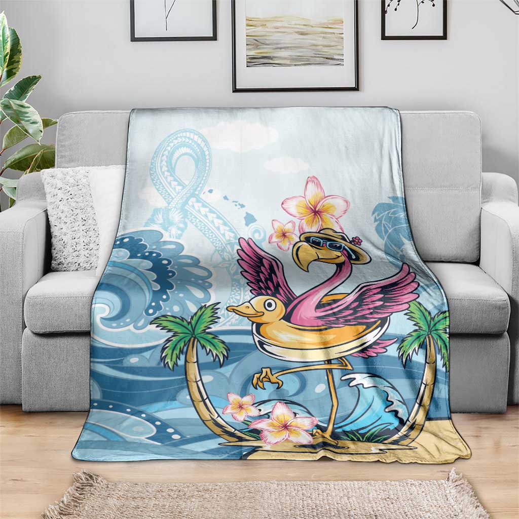 Blue flamingo throw blanket with plumeria flowers, laid over a gray sofa