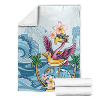 Folded blue tropical blanket with flamingo and plumeria flowers, stacked with white towels