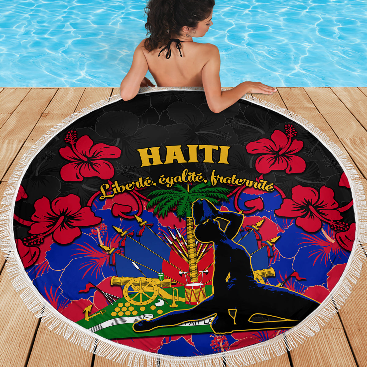 Round beach blanket showing Haiti emblem and red hibiscus flowers, black center, fringe trim