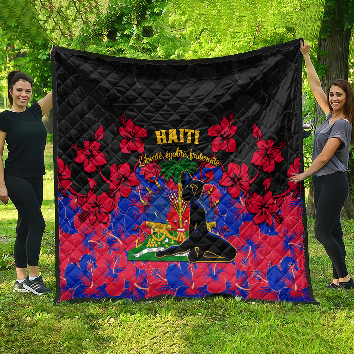Black Haiti-themed quilt draped outdoors with red hibiscus flowers and Haiti text