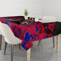 Black, red, and blue hibiscus print tablecloth with a hanging corner over the table.