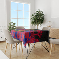 Black tablecloth with red and blue hibiscus floral print, placed on a dining table.