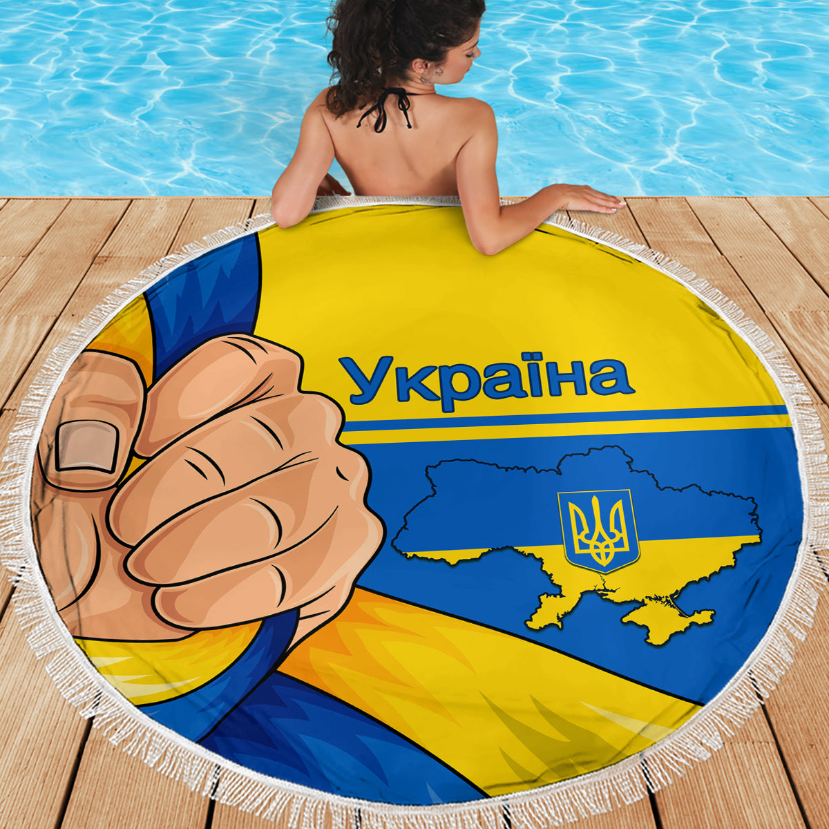 Round beach blanket with Ukraine flag graphic, comic fist and trident, on pool deck