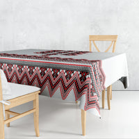Rectangular folk tablecloth draped on dining table; red, black, and white geometric border