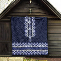 Navy blue quilt hanging on wall, with central geometric motif and zigzag stripe hem