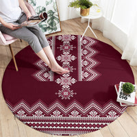 Wine red round rug with white folk stripes and diamond motifs along the border