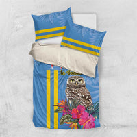 Blue duvet cover and pillowcases with tropical owl, pink flowers, and yellow stripe detailing.