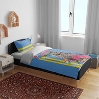 Blue duvet set on bed with tropical owl print, pink flowers, and bright yellow stripe accents.
