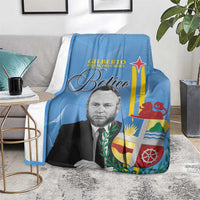 Blue Aruba flag style blanket draped on seating, showing portrait, star, and coat-of-arms