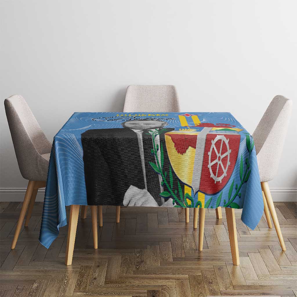 Blue Aruba flag-style tablecloth with colorful crest pattern on dining table and chairs