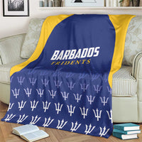 Barbados Tridents cricket blanket on armchair, blue center with yellow border and logo