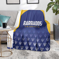 Barbados Tridents cricket blanket seated on gray rug, blue with yellow trim and trophy pattern