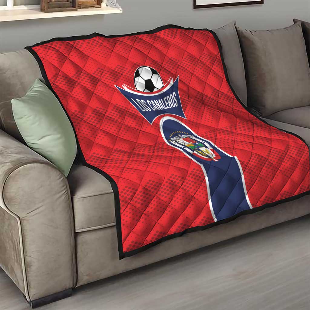 Red football quilt blanket with Los Canaleros crest over gray sofa arm