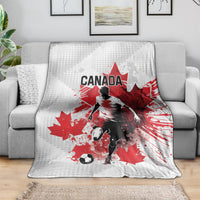 Canada soccer blanket on couch, white-and-gray with red maple leaf and footballer