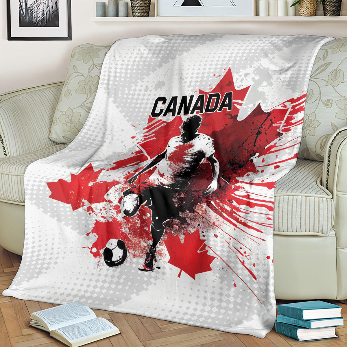 Canada soccer blanket draped on sofa, white-and-gray with red maple leaf scene