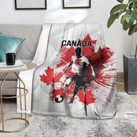 Canada soccer blanket on floor, white-and-gray fabric with red maple leaf and player