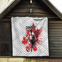White quilted blanket with Canada soccer player and red maple leaf, displayed on wall