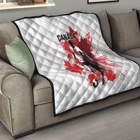 White quilted blanket with Canada soccer player and red maple leaf, draped over sofa