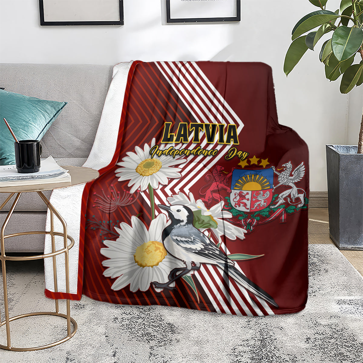 Red blanket with Latvia emblem, wagtail bird, and daisy flowers over gray sofa