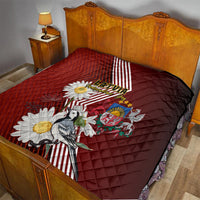 Red quilt on bed with Latvian stripes, daisies, crest emblem, and bird motif