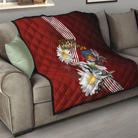 Red quilt on couch with Latvian stripes, daisies, crest badge, and bird illustration
