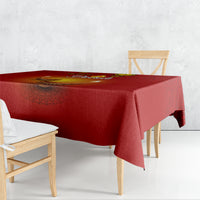 Red tablecloth spread across a dining table, paisley border with diya design in center.
