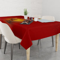 Red square tablecloth with diya and paisley print, draped over dining table corner.