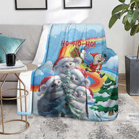 Blue Christmas blanket draped on couch, showing koalas, Santa, and rainbow 'HO-HO-HO'