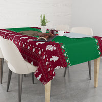 Christmas tablecloth on dining table with maroon geometric design, green panel and white pine trees
