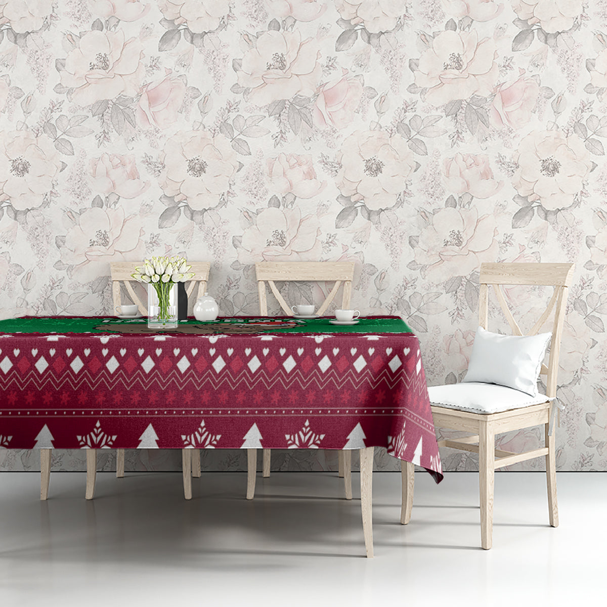 Christmas tablecloth on table with maroon geometric pattern, green strip, white pine trees and snowflakes